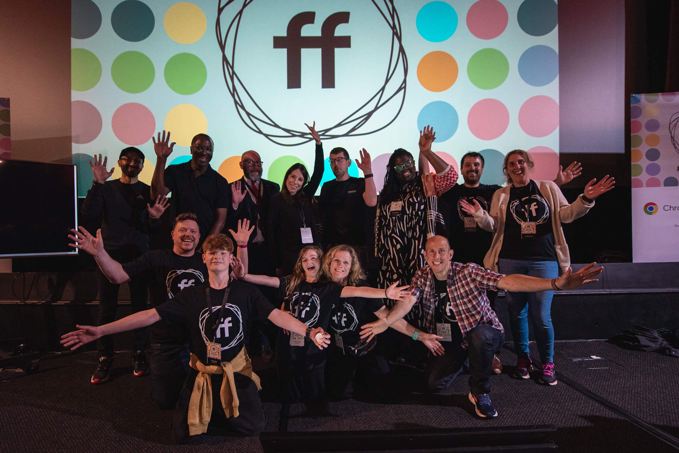 The conference organisers, and most of the 2024 speakers standing and waving on stage.